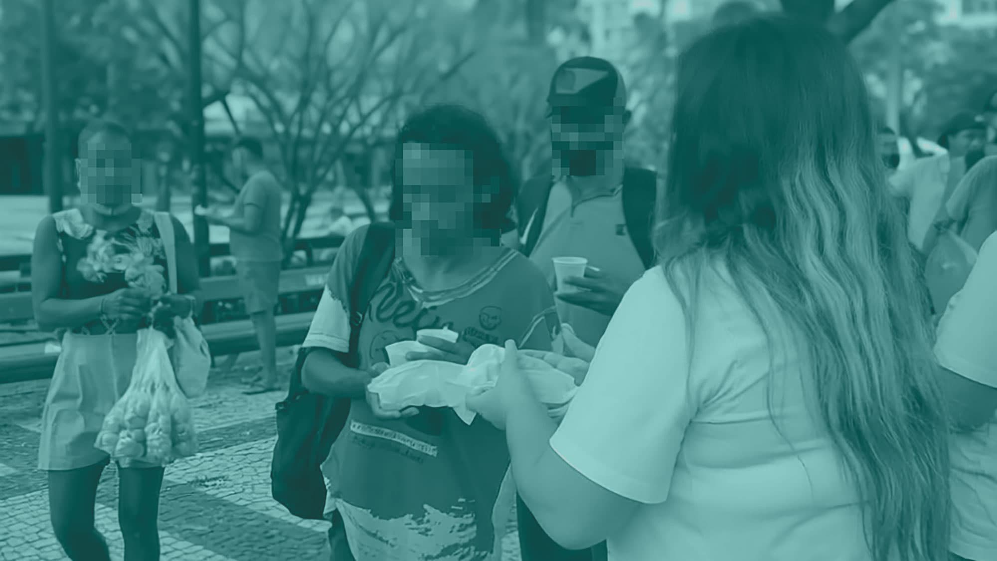Voluntária entregando alimento a uma pessoa em situação de rua